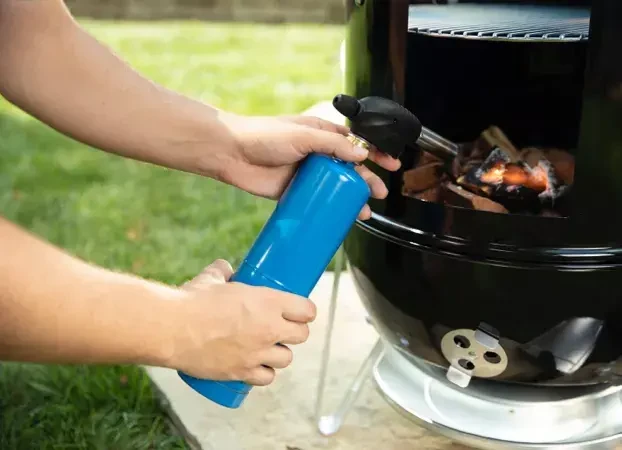 person lighting a smoker with a torch